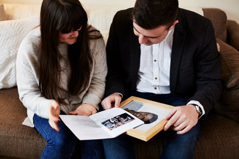 James & his sister, Katie sit on a sofa, looking at a photo of their dad, Peter