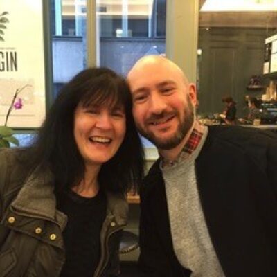 Man and woman sitting together, heads touching and smiling to camera