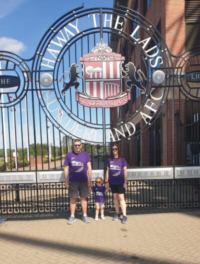Man, woman and child standing outside the sunderland afc grounds wearing pancreatic cancer uk tops for the big step forward