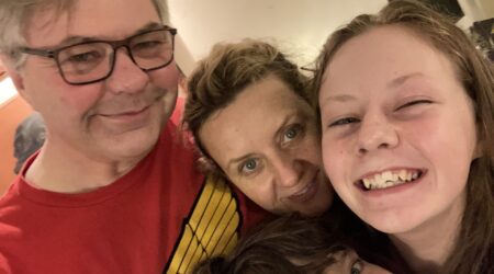 A man with glasses, a woman and two kids squeeze into the frame for a family selfie