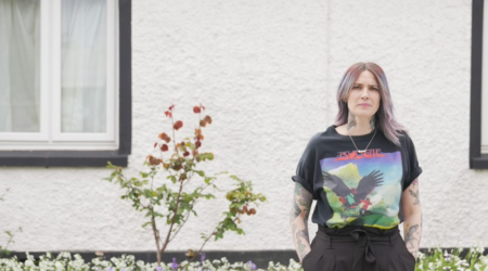 Woman standing in front of a white wall, with flowers.