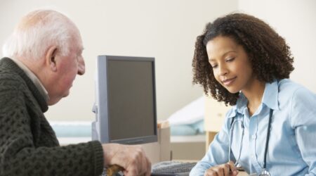 A doctor in a blue shirt speaking to an elderly patient