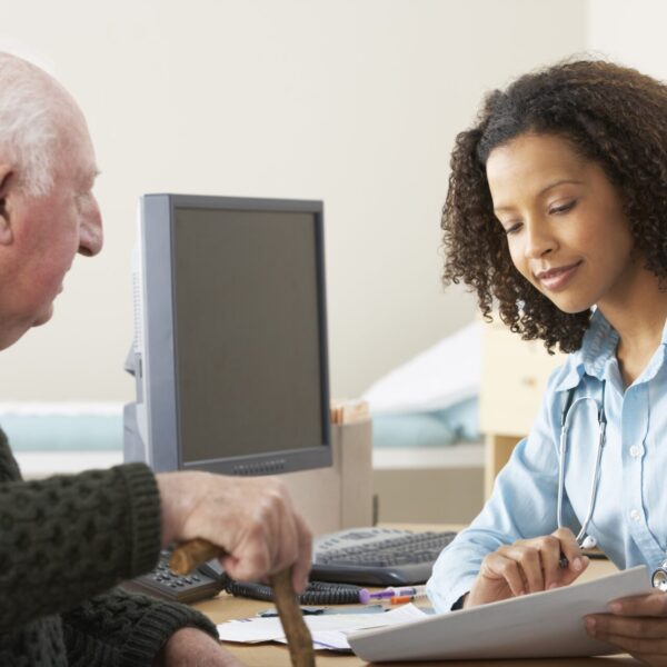 A doctor in a blue shirt speaking to an elderly patient
