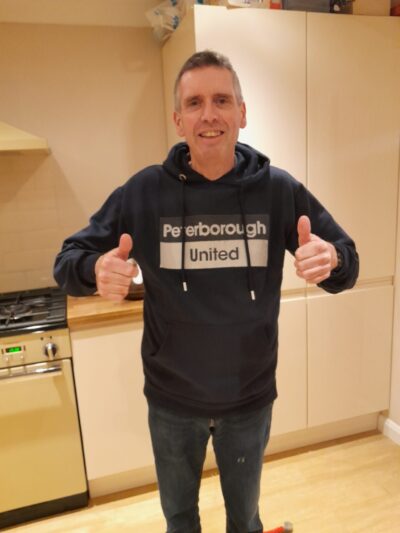 Man standing in kitchen, looking at camera and smiling with both thumbs up
