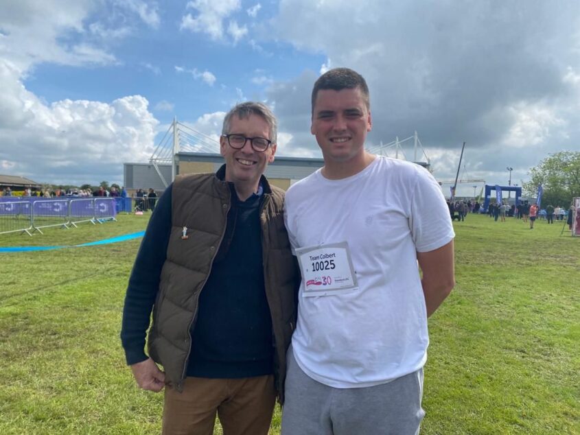 Man and his son standing together. The son has a competitor number on his t-shirt