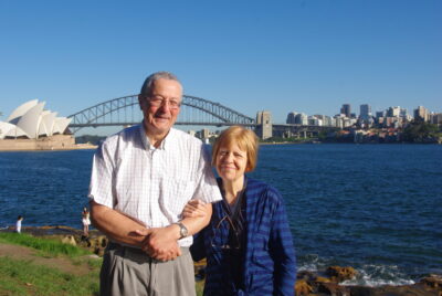 John and his wife Natalie standing in front of the Sydney Opera House and bridge