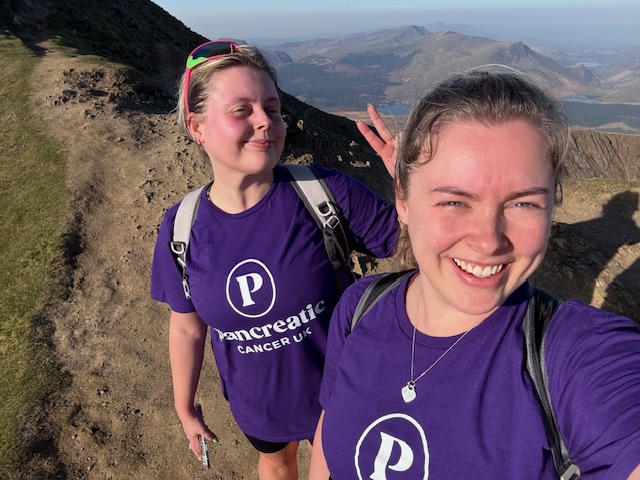 two girls in purple t-shirts on top of a mountain