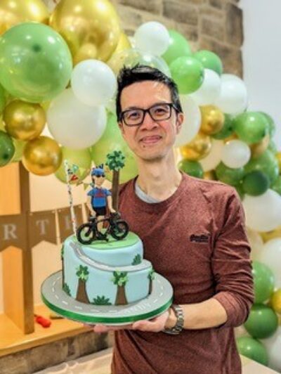 Man holding birthday cake decorated with a little model of a cyclist
