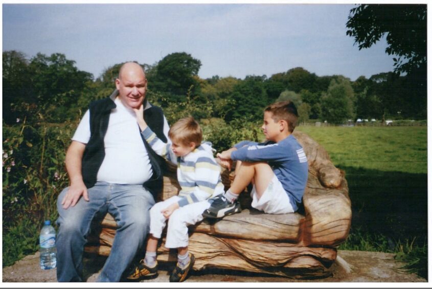 Man sitting on a carved wooden bench with two young children