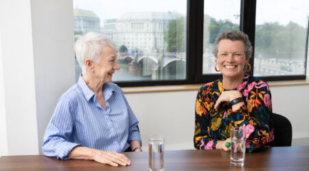 Maggie Blanks, CEO of Pancreatic Cancer Research Fund, and Diana Jupp, CEO of Pancreatic Cancer UK, laughing together in a meeting room.