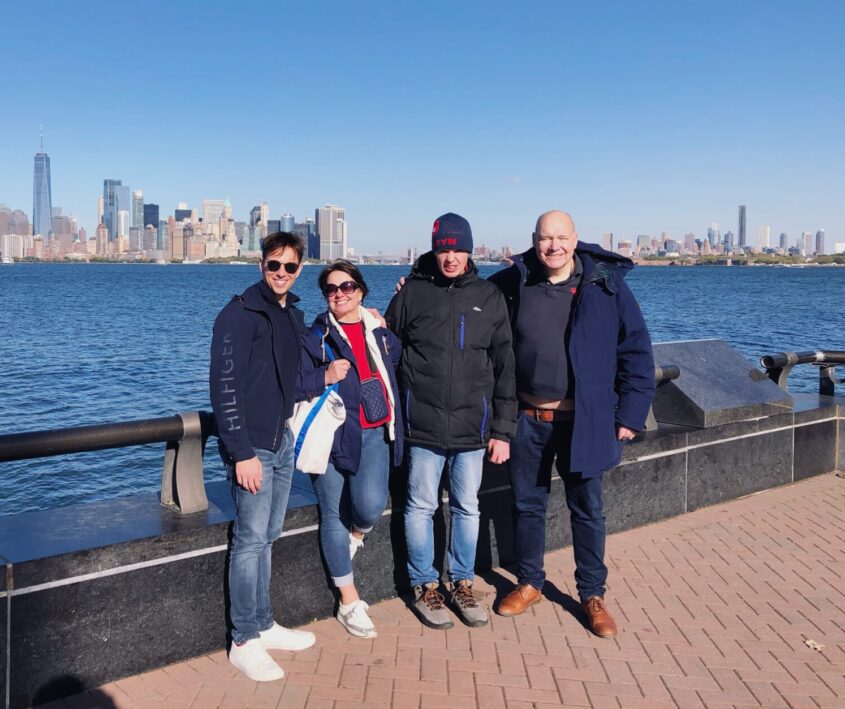 Family standing in front of large river with a city skyline behind