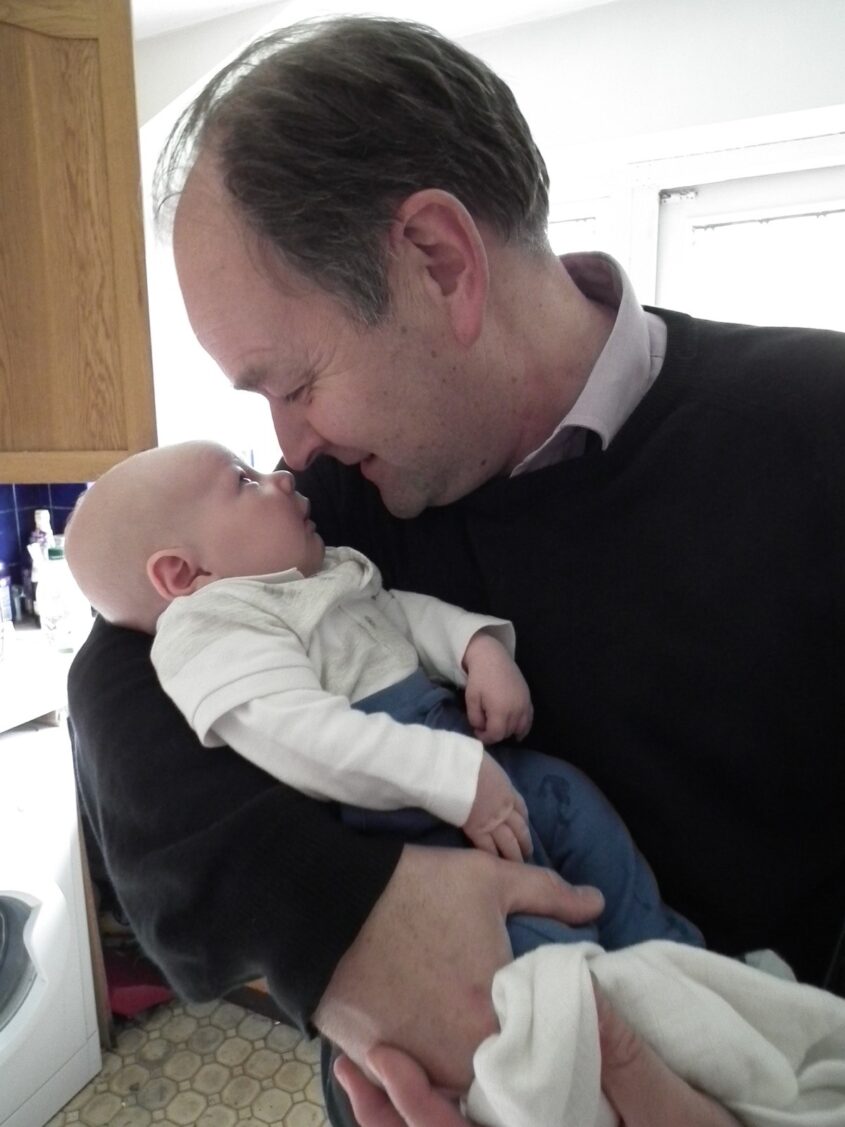Grandfather kissing new baby