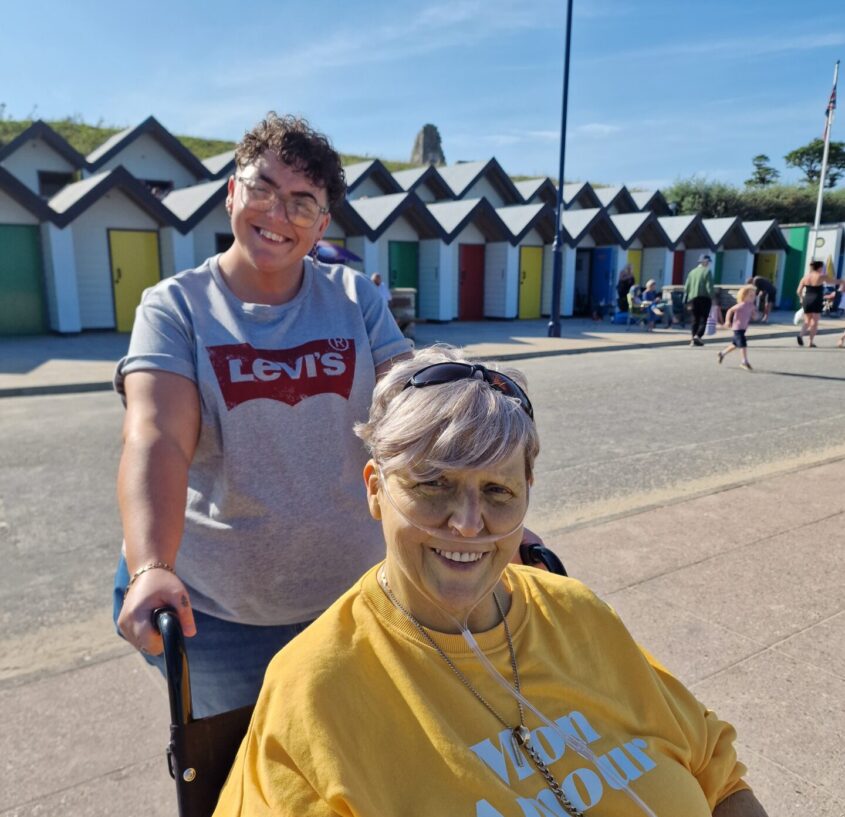 woman in wheelchair being pushed by daughter on beach prom