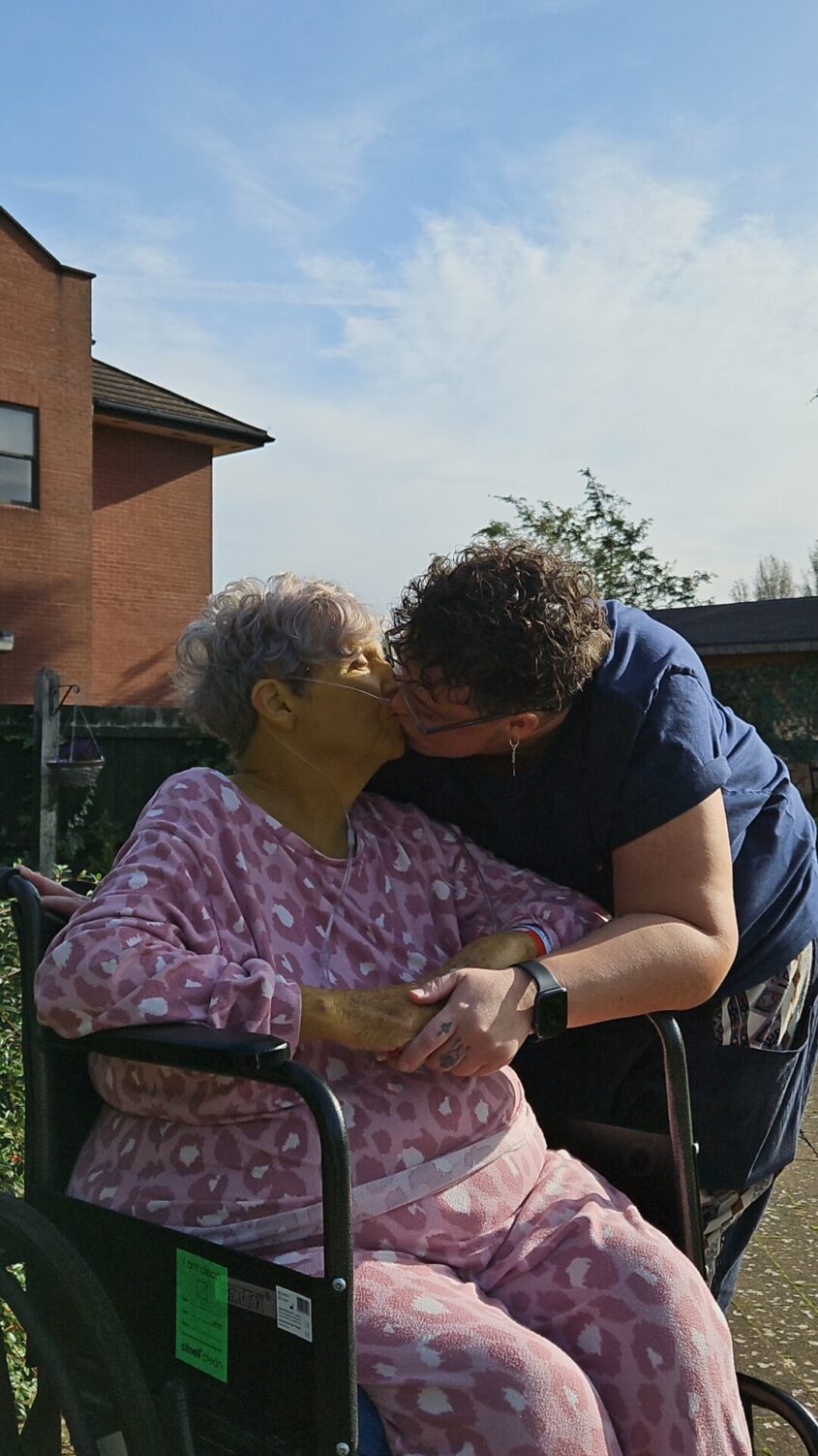 Woman in wheelchair getting a kiss from her daughter