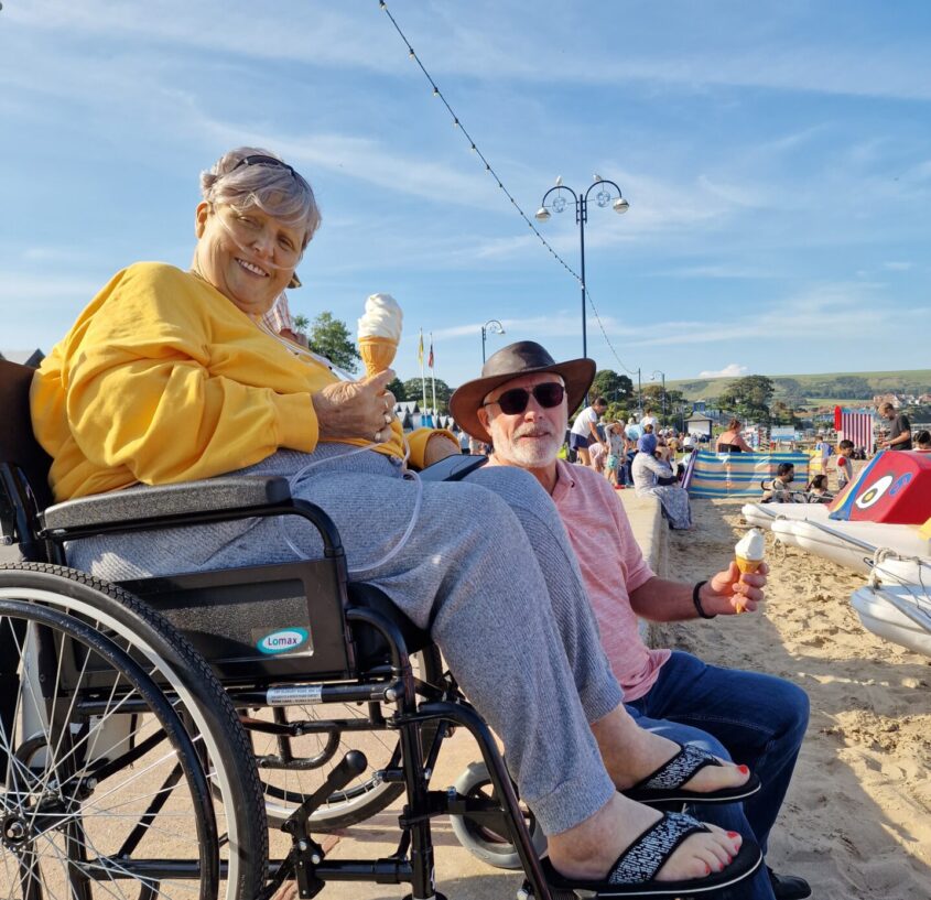 woman in wheelchair at the beach with an ice cream cone