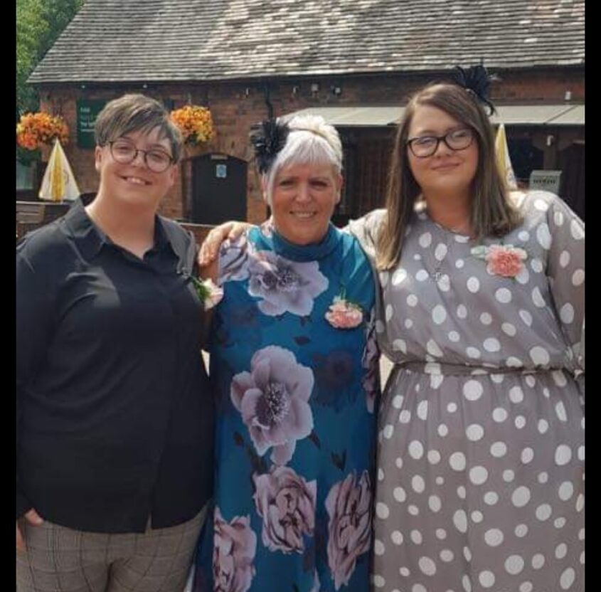 Three women standing, dressed in smart clothes all smiling to camera