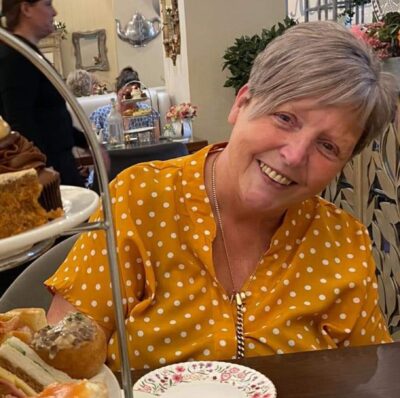 Woman wearing yellow top sitting in cafe, smiling at camera