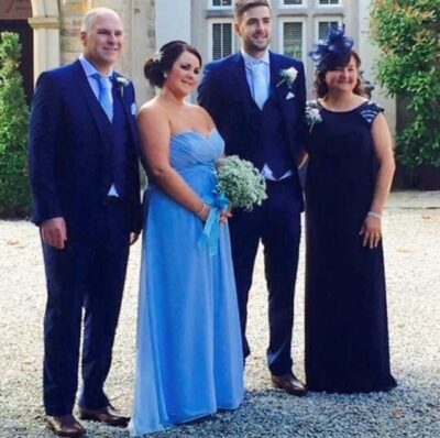 A young couple in wedding attire flanked by an older couple