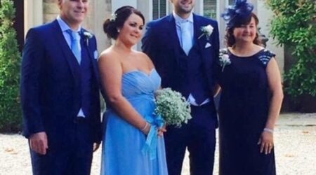 A young couple in wedding attire flanked by an older couple