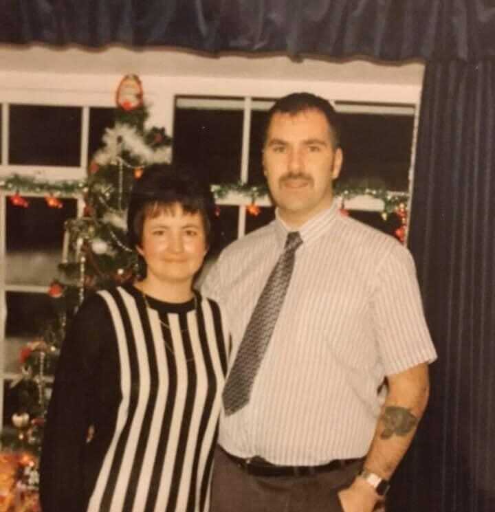 A young couple in the 1980s pose by the Christmas tree