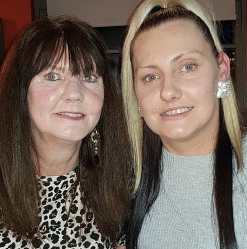 Older woman and younger woman close together, facing the camera and smiling