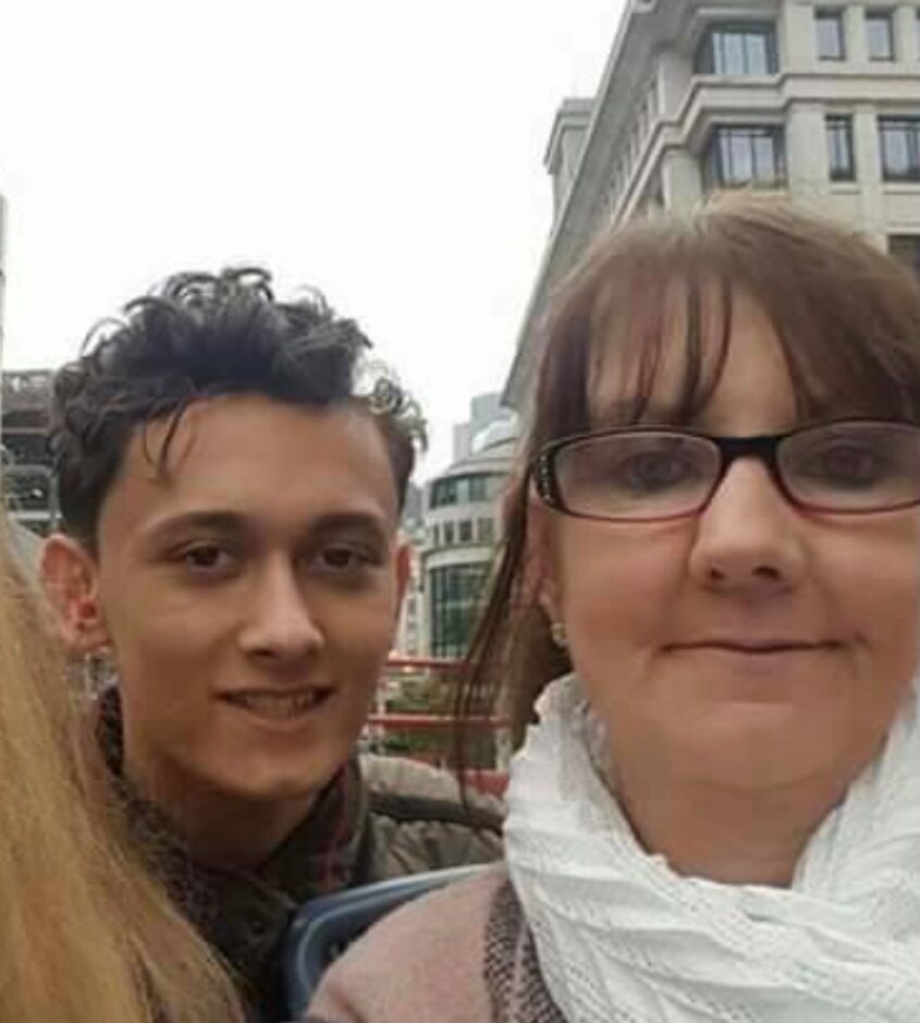 Selfie photo of older woman with glasses and younger man, both smiling to camera