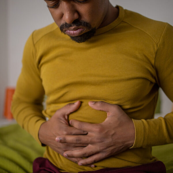 man holding his stomach, wearing a yellow shirt