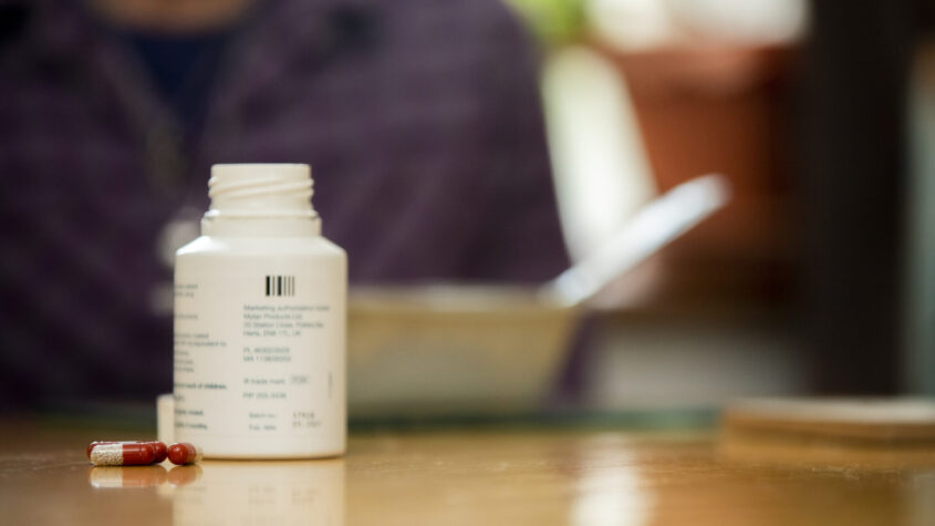 A bottle of pancreatic enzyme replacement therapy tablets on a table.