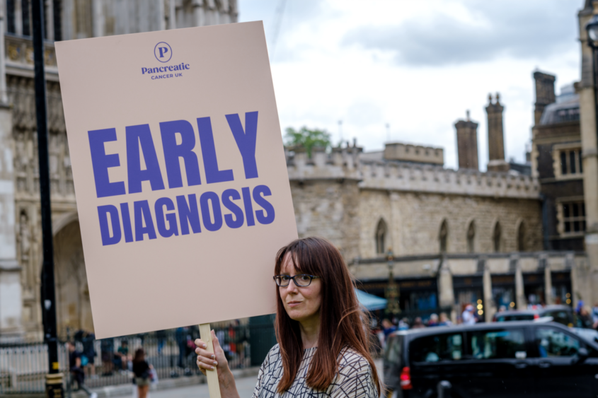 a person holding a sign reading early diagnosis