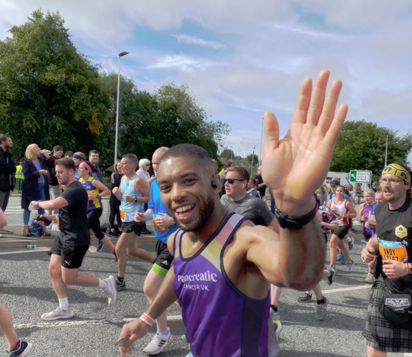 A person wearing the pancreatic cancer top running in a race, waving at the camera
