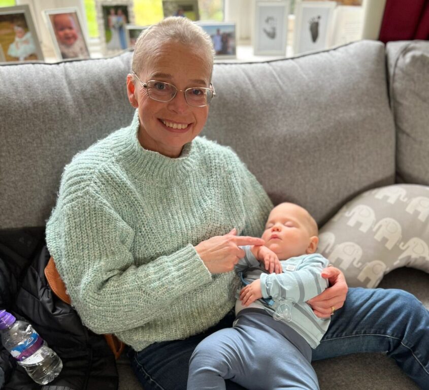 Woman sitting on sofa holding young baby
