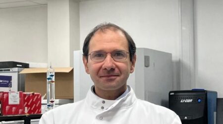 Male researcher wearing a lab coat looking at the camera