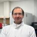 Male researcher wearing a lab coat looking at the camera