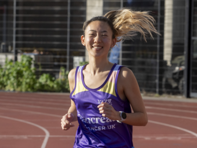 Claire running on a track in a Pancreatic Cancer UK running vest