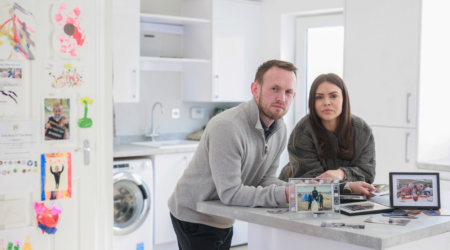 Siblings David and Lucy leaning over a kitchen counter next to some framed family photos
