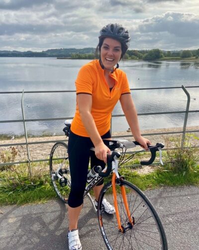 Young woman on a bike in front of a stretch of water