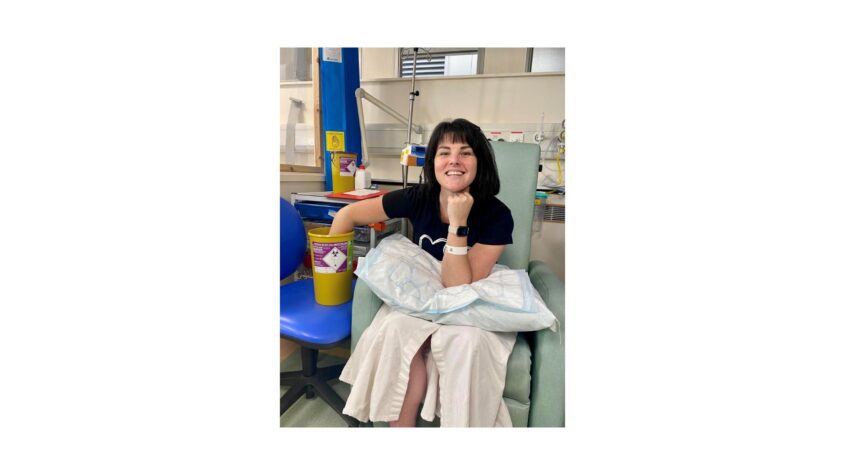 Emma smiling sat in a hospital chair
