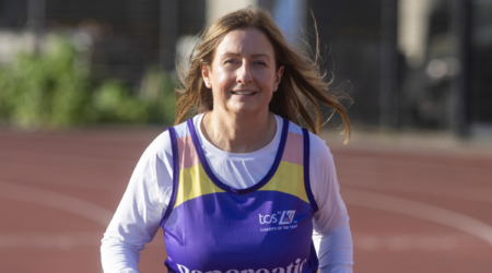 Jo running on a track wearing a Pancreatic Cancer UK running vest