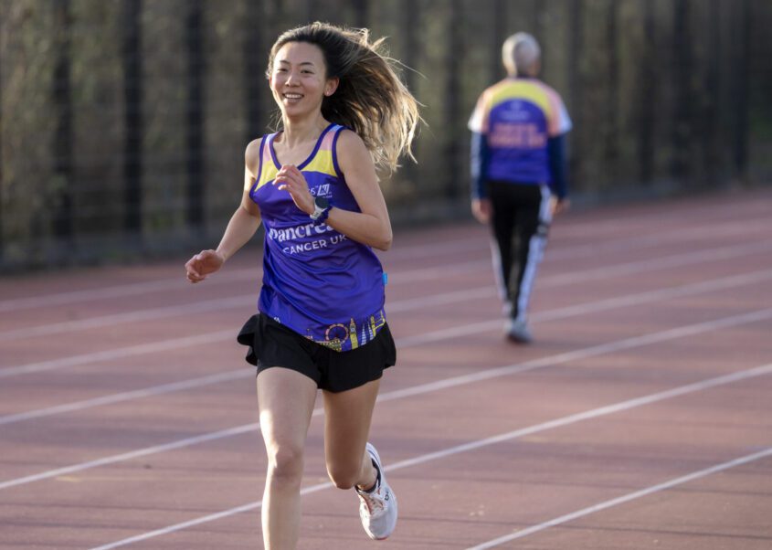Claire running on a track wearing a Pancreatic Cancer UK running vest