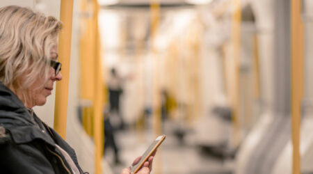 Middle aged woman looking at her phone on the tube