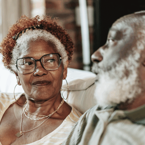 Two people sitting down looking at each other on a sofa