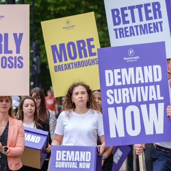 Team of PCUK staff with signs saying 'early diagnosis', 'more breakthroughs', demand survival now' and 'better treatment', walking towards Downing Street.