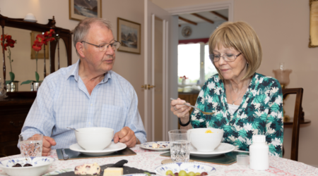Couple sitting at a table eating with a PERT bottle on the table