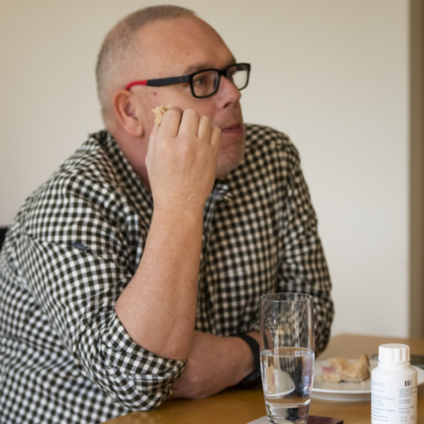 A man eating at a table with a PERT tablet bottle on the table
