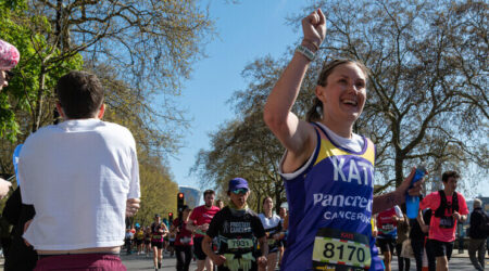 Woman running in a pancreatic cancer uk top on a bright day