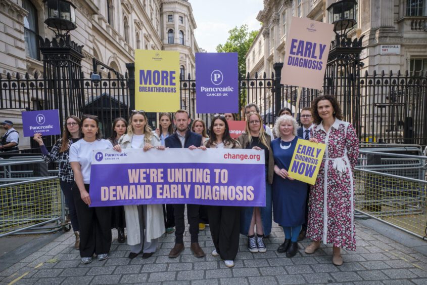 Group of fifteen stands by Whitehall holding signs and banners calling for early detection of pancreatic cancer