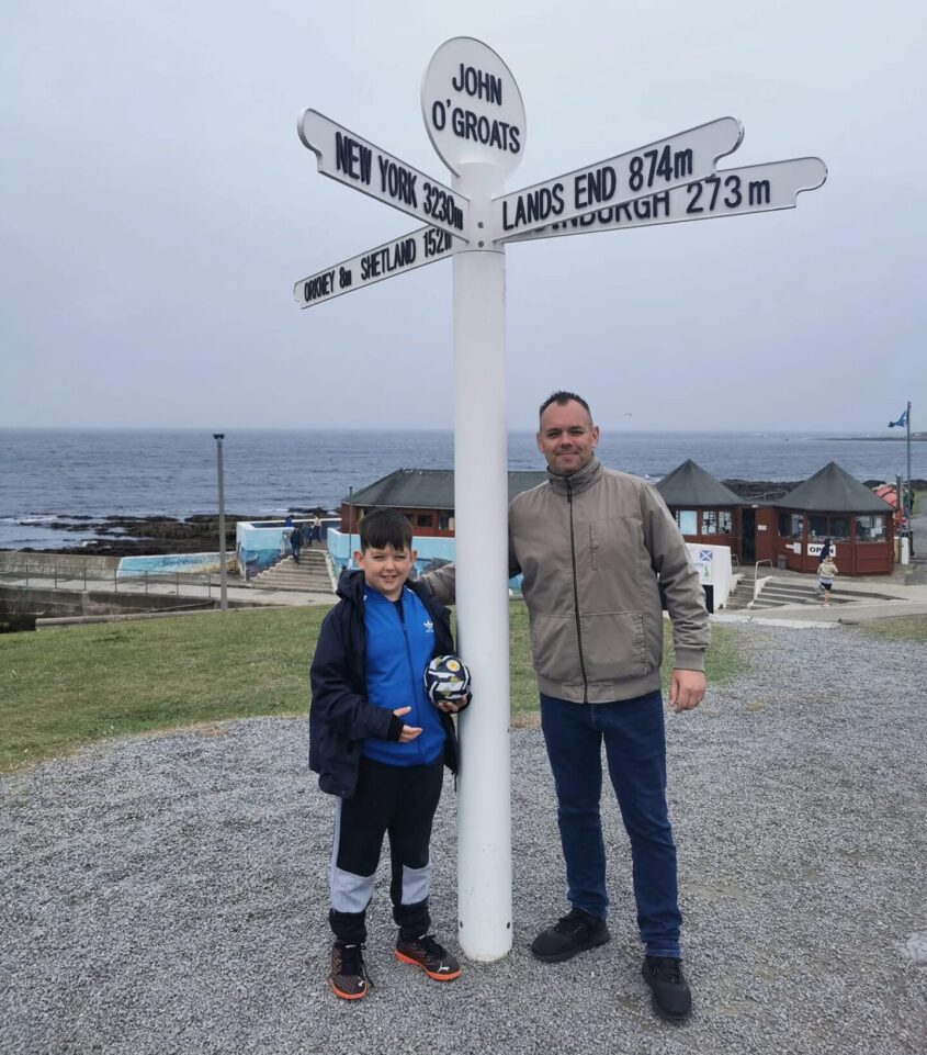 A young son and his dad stands next to the Lands End signage
