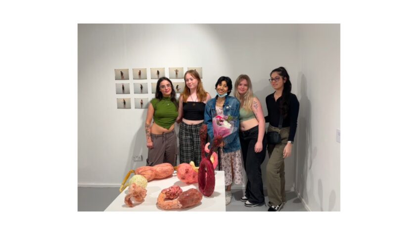 Group of young women standing in front of art exhibits all smiling