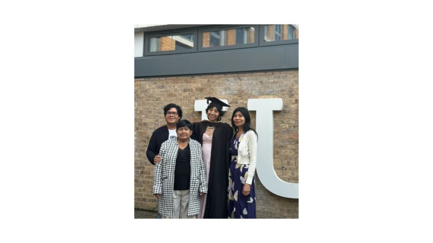 Young woman in graduation outfit standing in front of college or university with her family