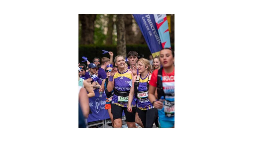 woman amongst marathon runners waving and smiling